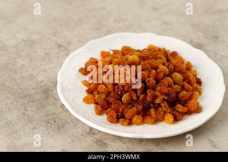 Raisins secs dorés séchés biologiques dans une assiette blanche Banque D'Images