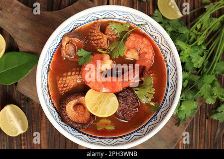 Tom Yam Kung, soupe de fruits de mer à la crevette épicée, est une recette populaire de soupe chaude et de sour thaï. Servi dans un bol en céramique, table en bois. Vue de dessus Banque D'Images