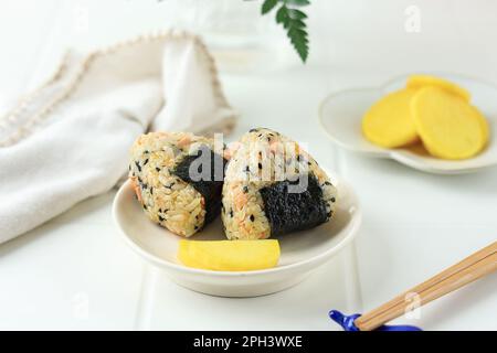 Triangle japonais Onigiri avec graines de sésame, saucisse, Nori, et Ham. Servi avec Takuan Banque D'Images