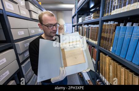 PRODUCTION - 21 mars 2023, Saxe-Anhalt, Halle (Saale): Jens Wehmann, bibliothécaire à la Maison du Handel à Halle/Saale, présente des documents historiques du 1940s dans les archives de la Maison du Handel. Les archives du musée et lieu de naissance du compositeur baroque George Frideric Handel (1685-1759) sont conservées pour la postérité. Environ 200 boîtes de fichiers ont été désacidifiées et ainsi sauvées de la décomposition du papier. Les dossiers comprennent la correspondance des directeurs de la Maison Handel, la correspondance sur les achats, l'organisation du Festival Handel et des documents sur l'organisation de l'exposition Banque D'Images