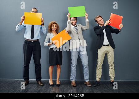 Vous méritez d'être entendu. Photo en longueur d'un groupe de jeunes hommes d'affaires créatifs tenant des pancartes vierges dans leur bureau. Banque D'Images
