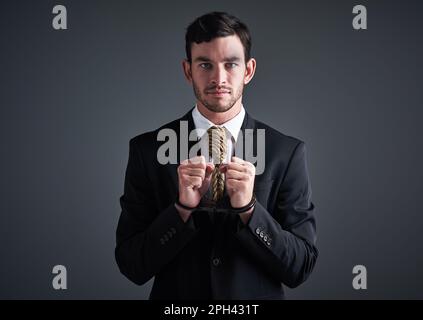 Ne laissez pas les pratiques commerciales malhonnêtes vous retenir dans les affaires. Studio portrait d'un homme d'affaires menotté avec un nœud attaché autour de son cou pour un Banque D'Images