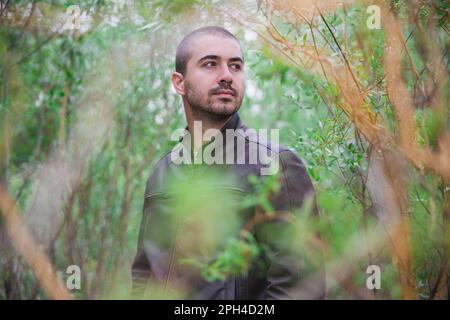 un homme attrayant dans une veste en cuir est en marche dans la jungle Banque D'Images