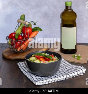 Un bol contenant du riz blanc avec des légumes hachés et des feuilles de basilic à côté d'un panier de légumes entiers et d'une bouteille d'olive extra vierge italienne Banque D'Images