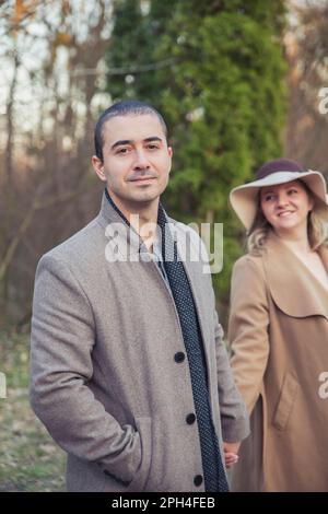 Couple marié en manteau marchant dans le parc d'automne Banque D'Images