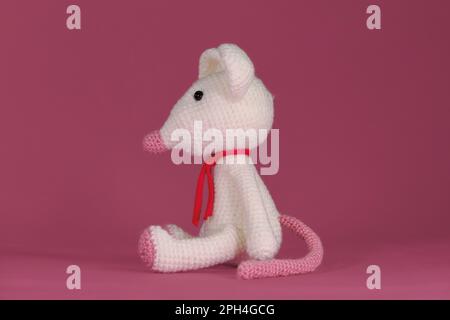 Un jouet de bricolage doux en coton naturel et laine. Mignon petit rat crocheté, art fait à la main Amigurumi une souris blanche avec de grandes oreilles et un long nez sur un Banque D'Images