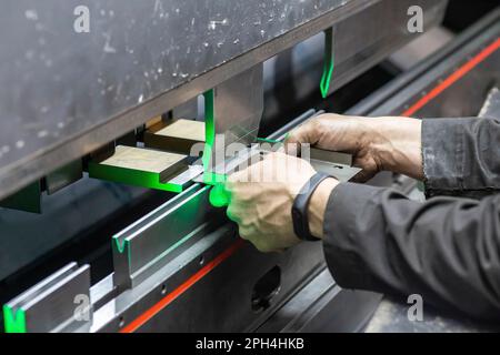 L'employé tient une pièce dans une machine de cintrage CNC Banque D'Images