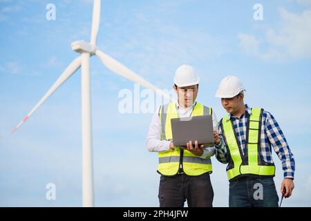 Deux ingénieurs asiatiques discutent et vérifient les éoliennes dans un parc d’éoliennes. Technologie des énergies renouvelables et durabilité. Banque D'Images