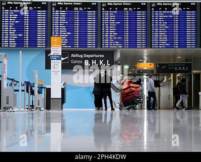 Munich, Allemagne. 26th mars 2023. Les passagers se trouvent devant le panneau d'affichage de l'aéroport de Munich. L'aéroport de Munich est déjà en grève un jour avant la grande grève d'avertissement qui paralysera de grandes parties des transports en commun lundi prochain. Les services ferroviaires interurbains, les aéroports, les bus et les trains dans sept États allemands sont touchés. Credit: Angelika Warmuth/dpa/Alamy Live News Banque D'Images