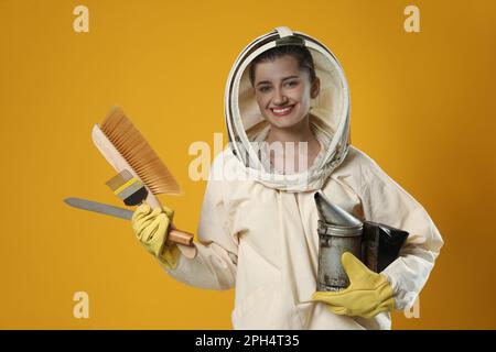 Apiculteur en uniforme avec outils sur fond jaune Banque D'Images