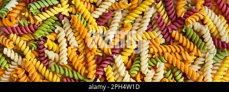 Pâtes italiennes colorées sur fond blanc. Pâte pour enfants avec colorants naturels de légumes et d'herbes. Fond de pâtes.bannière. Banque D'Images