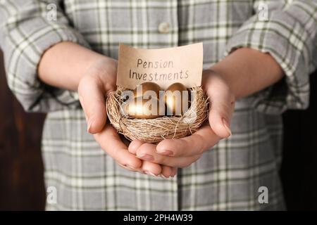 Femme tenant des oeufs d'or et la carte avec l'expression Pension Investments dans le nid, fermé Banque D'Images