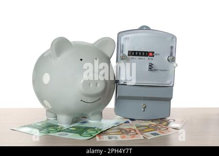 Compteur d'électricité, banc de pigey et argent sur table en bois sur fond blanc Banque D'Images