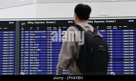 Munich, Allemagne. 26th mars 2023. Un passager se tient devant le panneau d'affichage de l'aéroport de Munich. L'aéroport de Munich est déjà en grève un jour avant la grande grève d'avertissement qui paralysera de grandes parties des transports en commun lundi prochain. Les services ferroviaires interurbains, les aéroports, les bus et les trains dans sept États allemands sont touchés. Credit: Angelika Warmuth/dpa/Alamy Live News Banque D'Images