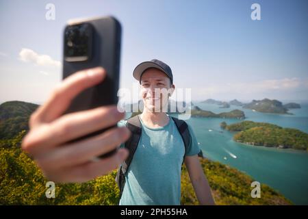 Homme souriant avec sac à dos prenant le portrait de selfie sur la colline contre groupe d'îles tropicales en mer. Parc marin national ANG Thong près de Koh Samui dans le Th Banque D'Images