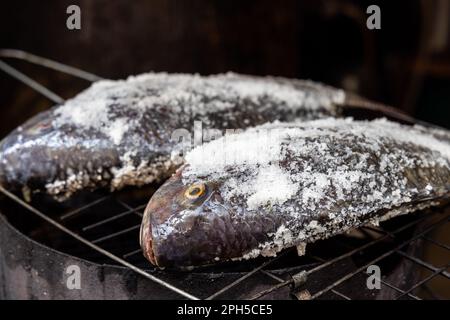 Le poisson barbecue en croûte de sel est populaire dans la rue en Thaïlande. Le poisson est masqué avec du sel et prêt à être grillé Banque D'Images