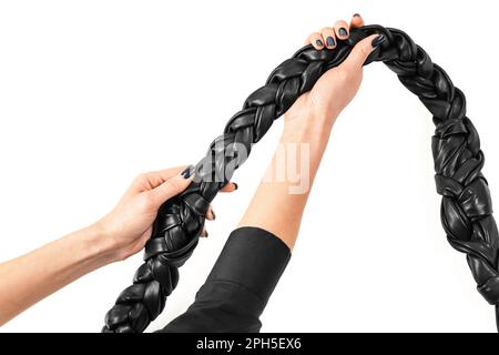Mains de femmes tenant une bandoulière tressée en cuir noir véritable isolée sur fond blanc. Concept de publicité des produits en cuir faits main Banque D'Images
