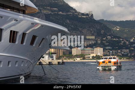 Contraste entre le paquebot de croisière Cunard Queen Elizabeth's Tender et un super yacht de luxe dans le Port Hercule, Monte Carlo, Monaco. Banque D'Images