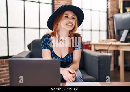 Jeune femme caucasienne musicienne souriant confiante en utilisant un ordinateur portable dans un studio de musique Banque D'Images