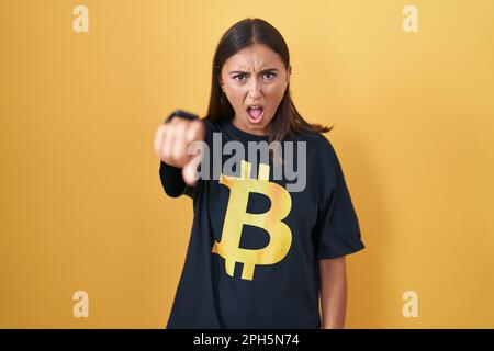 Jeune femme hispanique portant le t-shirt bitcoin pointant mécontente et frustrée de la caméra, en colère et furieux avec vous Banque D'Images