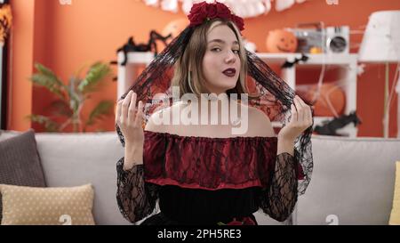 Jeune femme blonde portant le costume katrina assise sur un canapé à la maison Banque D'Images