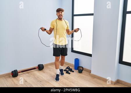 Homme arabe avec la formation de barbe avec corde de saut en collant la langue dehors heureux avec l'expression drôle. Banque D'Images