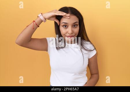 Jeune femme arabe portant un t-shirt blanc décontracté sur fond jaune inquiet et stressé au sujet d'un problème de main sur le front, nerveux et anxieux f Banque D'Images