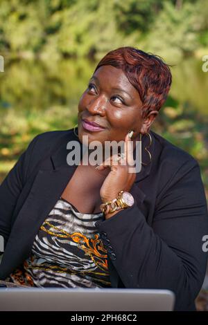 Photo d'une femme d'affaires afro-américaine regardant vers le haut et à côté avec la main sur la joue Banque D'Images