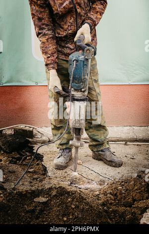 Homme constructeur travaillant avec un marteau à inertie frappant une surface dure Banque D'Images