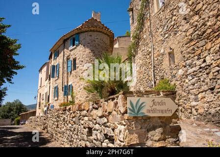 Un panneau mène à travers le pittoresque village médiéval de Roquebrun au jardin méditerranéen en passant par une maison particulière avec un coin rond. Banque D'Images