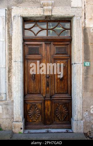 Une ancienne porte en bois aux motifs art devo dans le village de Roquebrun dans le sud de la France. Banque D'Images