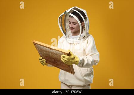 Apiculteur en forme de ruche de maintien uniforme avec nid d'abeille sur fond jaune Banque D'Images