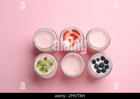Yaourt savoureux dans des pots en verre et ingrédients sur fond rose, plat Banque D'Images