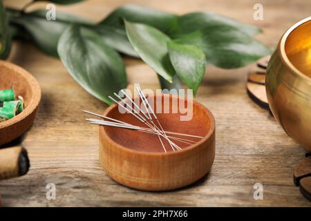 Bol avec aiguilles d'acupuncture sur table en bois Banque D'Images