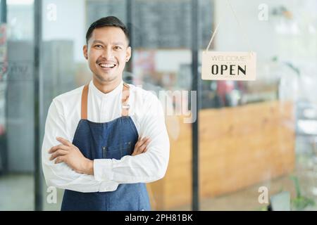 Portrait d'un bel homme asiatique dirigeant une petite entreprise montrant un visage souriant, un propriétaire de café ouvrant une boutique pour accueillir les clients dans la nouvelle Banque D'Images