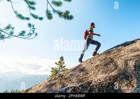 Défis, succès et réalisation dans les affaires et la vie. Image conceptuelle ambitieuse de l'homme de randonnée en forme d'homme en escalade et en randonnée dans la montagne raide Banque D'Images