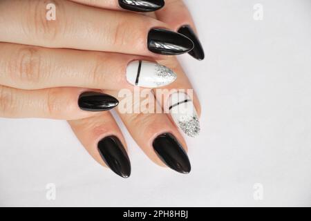 ongles prolongés avec manucure de couleur noire et blanche sur fond blanc, manucure féminine Banque D'Images