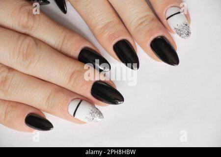 ongles prolongés avec manucure de couleur noire et blanche sur fond blanc, manucure féminine Banque D'Images