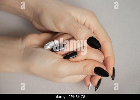 ongles prolongés avec manucure noire et blanche sur fond gris, manucure féminine Banque D'Images