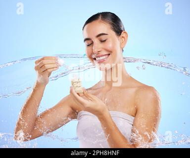 Femme heureuse, compte-gouttes et eau pour le sérum, le produit ou la crème de soin de la peau sur fond bleu studio. Femme calme sourit tenant la pipette pour Banque D'Images