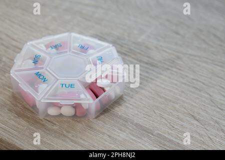 Organiseur injections hebdomadaires gros plan de la boîte de pilules médicales avec des doses de comprimés pour la journée prendre des médicaments avec des médicaments blancs roses et des capsules. Vitamines quotidiennes à la maison. Médicaments compléments alimentaires, immunité et prévention des maladies huile de poisson gel Softgel, vitamine D et C minéraux oméga, fibres, acides aminés gras, probiotiques sédatifs. Les soins de santé et les maladies guérissent Banque D'Images