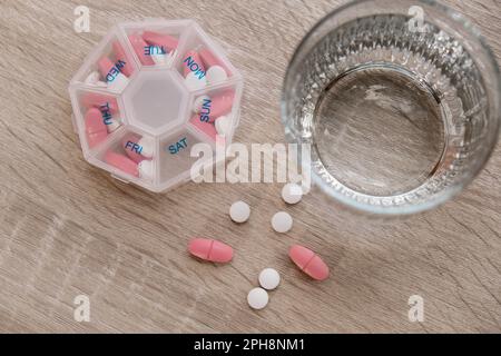 Organiseur injections hebdomadaires gros plan de la boîte de pilules médicales avec des doses de comprimés pour la journée prendre des médicaments avec des médicaments blancs roses et des capsules. Vitamines quotidiennes à la maison. Médicaments compléments alimentaires, immunité et prévention des maladies huile de poisson gel Softgel, vitamine D et C minéraux oméga, fibres, acides aminés gras, probiotiques sédatifs. Les soins de santé et les maladies guérissent Banque D'Images