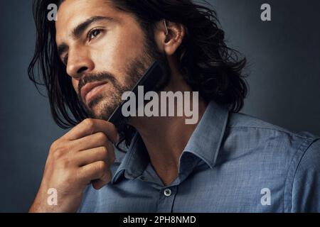 J'adore le style barbu. Photo en studio d'un jeune homme charmant peignant sa barbe sur un fond gris. Banque D'Images