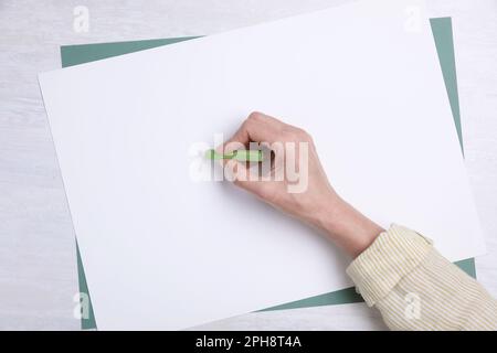 Femme dessin sur papier pastel à table en bois blanc, vue de dessus Banque D'Images