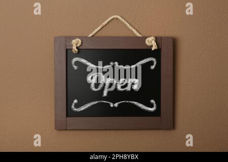 Petit tableau à craie avec le mot Open sur un mur brun Banque D'Images