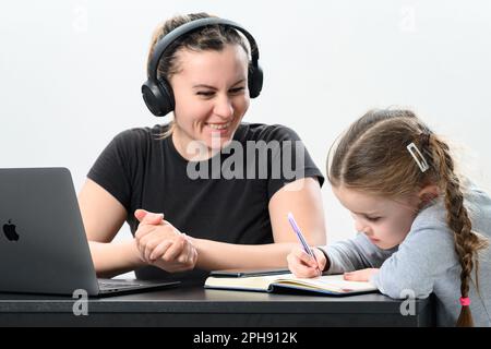 Ivano-Frankivsk, Ukraine 28 janvier 2023 : fille dans casque sans fil sur fond blanc avec pomme portable et fille, casque jbl et copie sp Banque D'Images