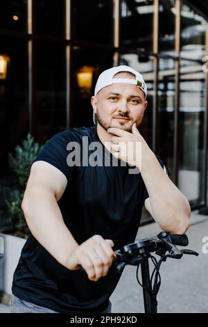 Agréable homme souriant à cheval. Un homme heureux à monter en scooter Banque D'Images