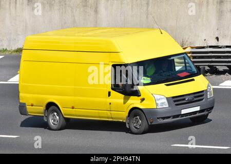 Conducteur d'un véhicule commercial dans une vue latérale et avant d'une fourgonnette jaune Ford Transit à toit surélevé propre et non marquée conduisant le long de la route d'autoroute M25 Essex Angleterre Royaume-Uni Banque D'Images