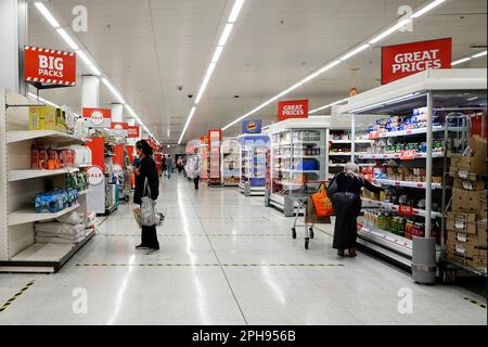 Coronavirus shopping gens dans Covid 19 masques de visage intérieur Sainsburys supermarché magasin corona virus social distance bande sur le plancher Essex Angleterre Royaume-Uni Banque D'Images