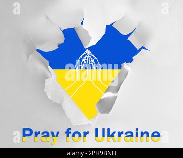 Priez pour l'Ukraine. Drapeau ukrainien avec illustration des mains, vue à travers le trou en forme de coeur dans le livre blanc avec l'expression Banque D'Images